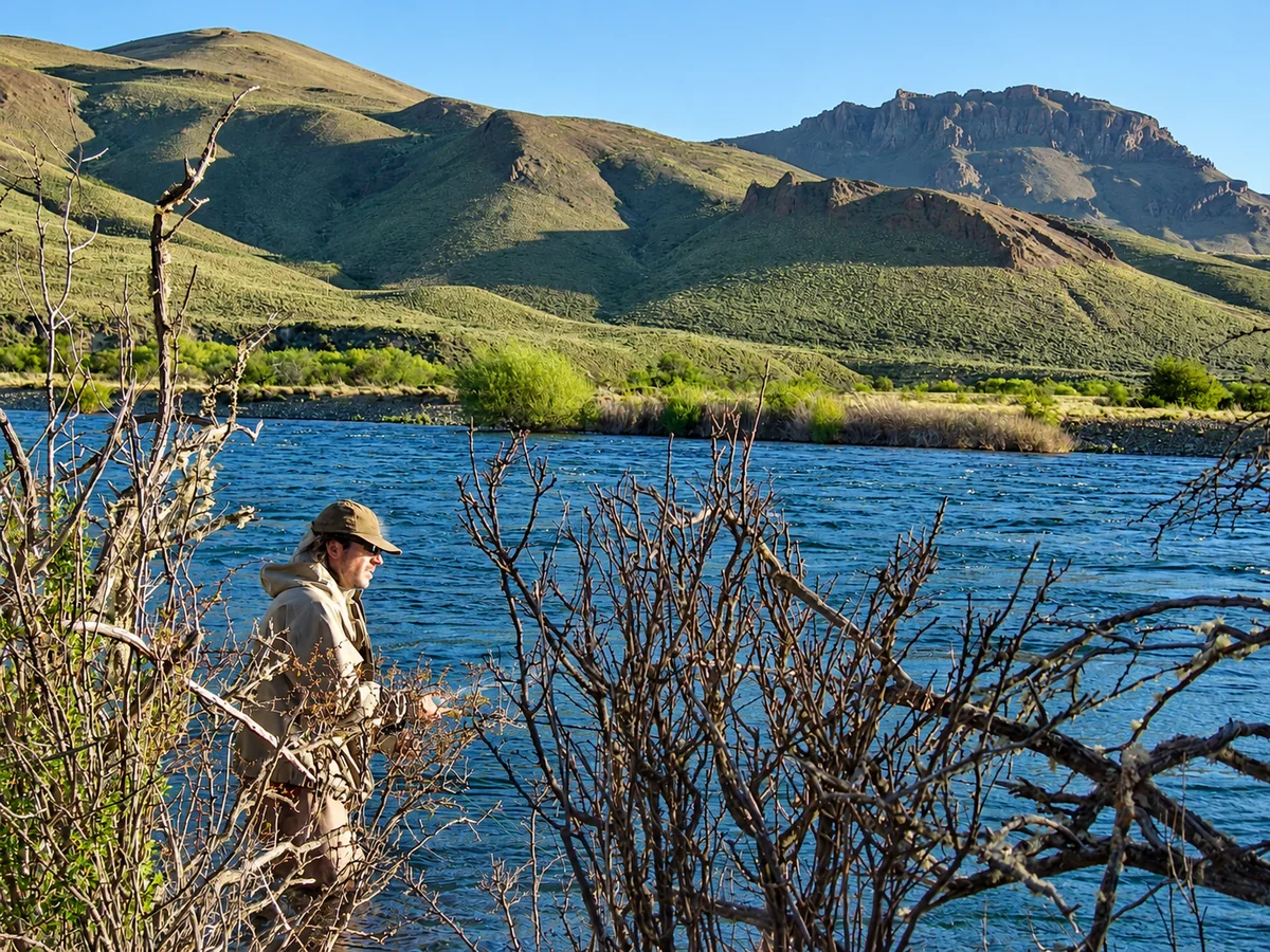 Angler managing a fly line beside a river in the Patagonian steppe
