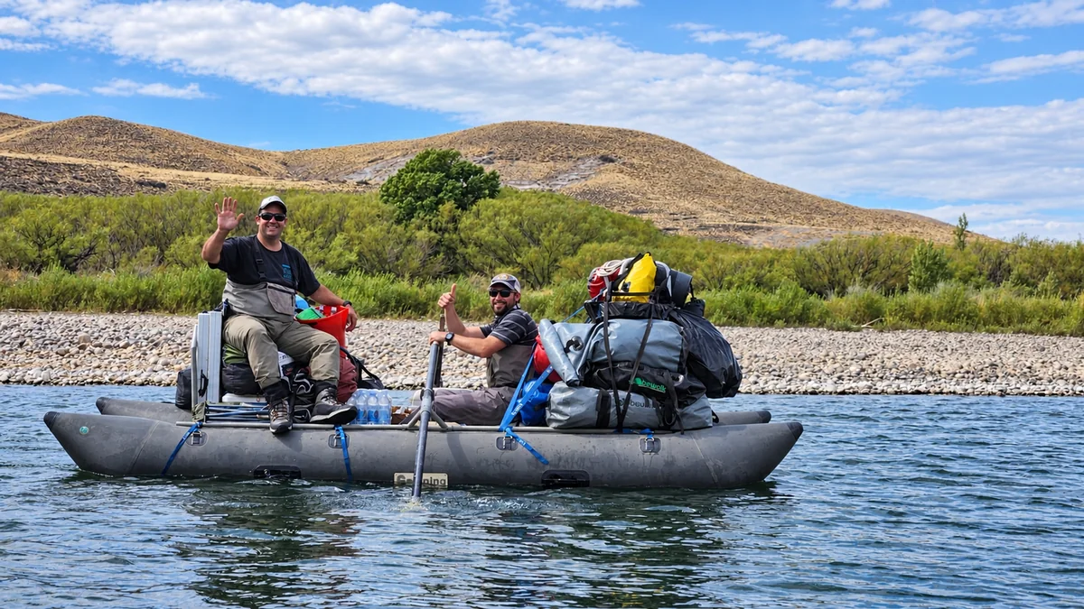 El equipo de apoyo de una expedición de pesca rema una balsa cargada con equipo de campamento en Patagonia