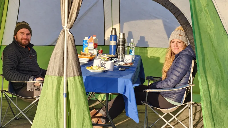 Viajeros compartiendo una comida en la carpa comedor de un campamento de pesca