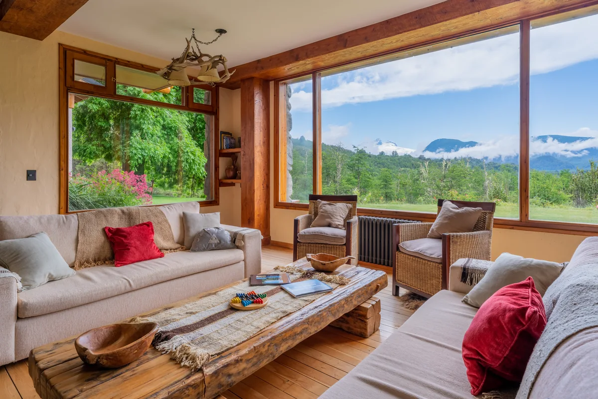 Fishing lodge living room with sofas and large windows overlooking the forest and mountains in Patagonia