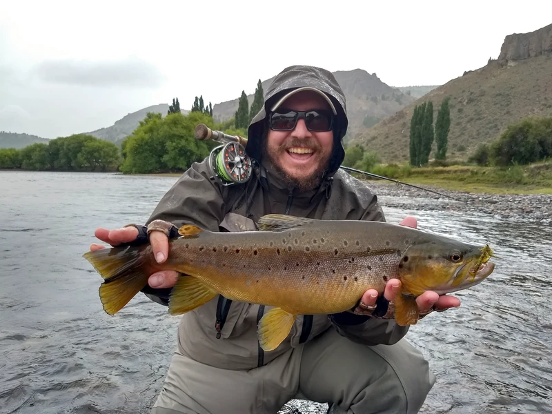 Pescador con una trucha marrón durante una salida de medio día de pesca con mosca en el río Limay