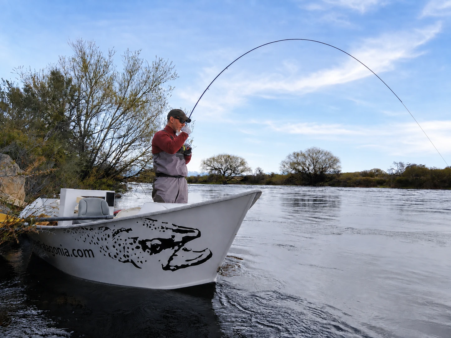 Angler fighting a trout from a drift boat near Bariloche