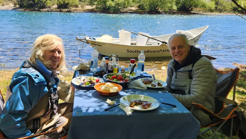 Pescadores compartiendo un almuerzo junto a un bote de deriva en el río Limay, Patagonia