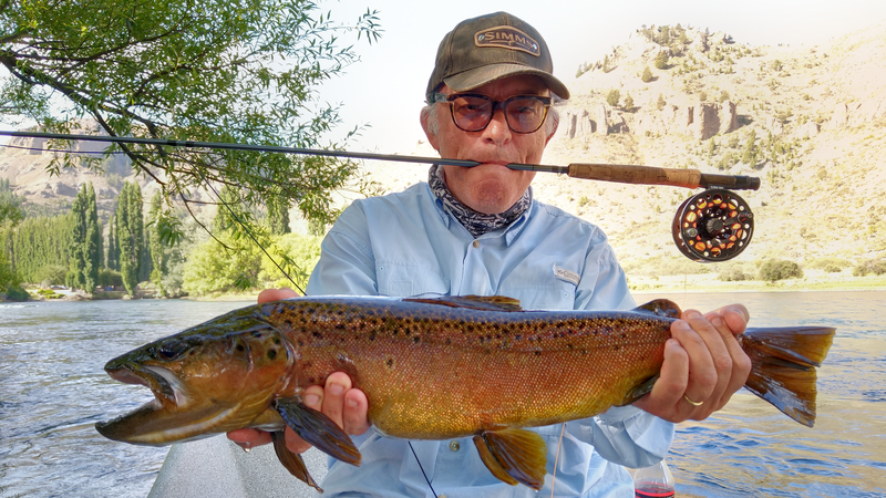 Angler holding a brown trout from a boat on the Limay River near Bariloche
