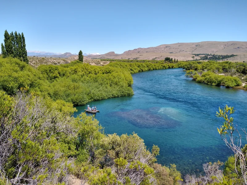 Anglers floating the clear waters of the Limay River among willow trees in Patagonia