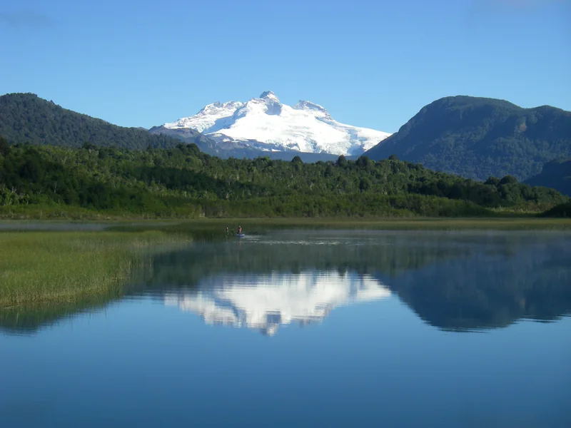 Snowy mountains reflected in Hess Lake beside a fishing raft in Patagonia