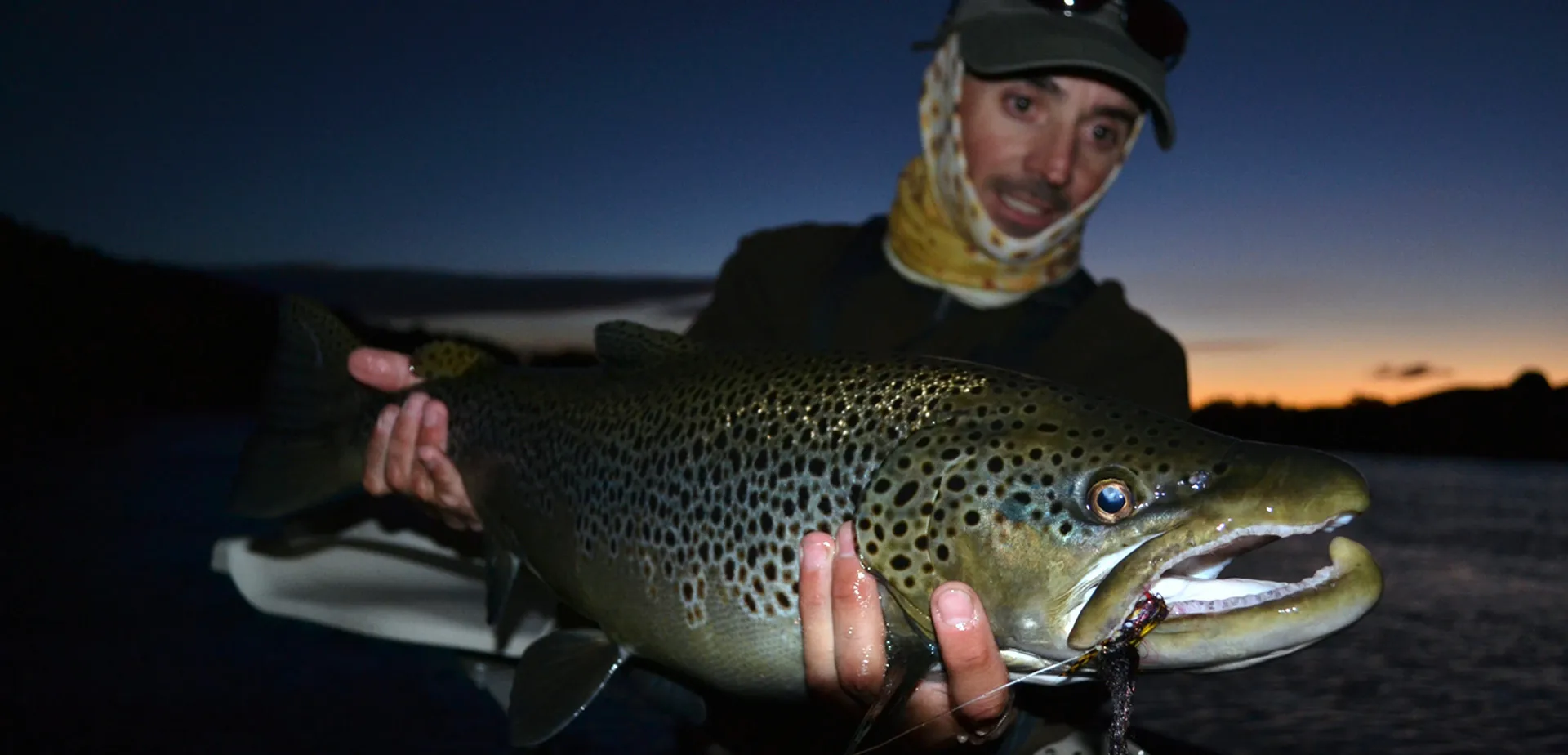 The professional fishing guide Lucas Valenti showing a big migratory brown trout in Bariloche Argentina Patagonia