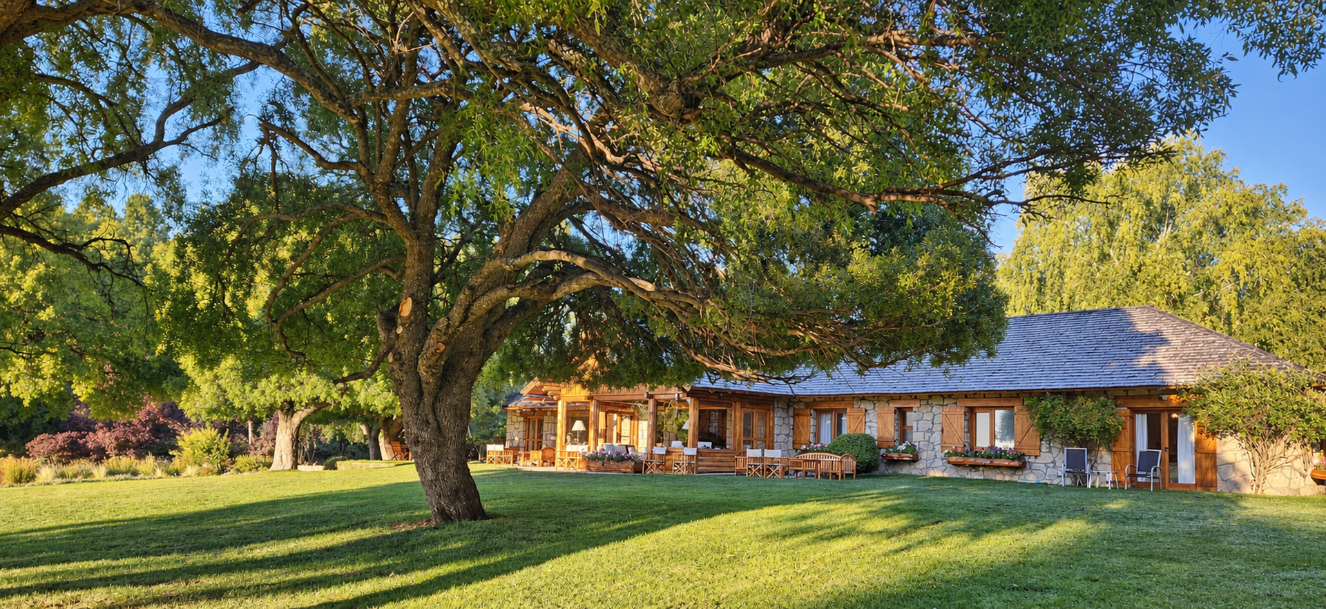 Estanca Arroyo Verde Fishing lodge with a stone and timber facade and sunlit gardens in autumn