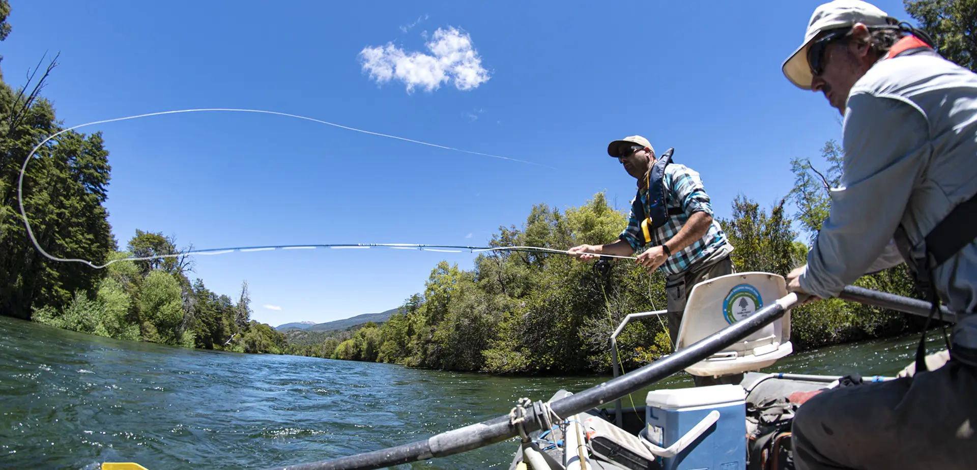 Guide rowing a drift boat while an angler casts on the Manso River in Patagonia