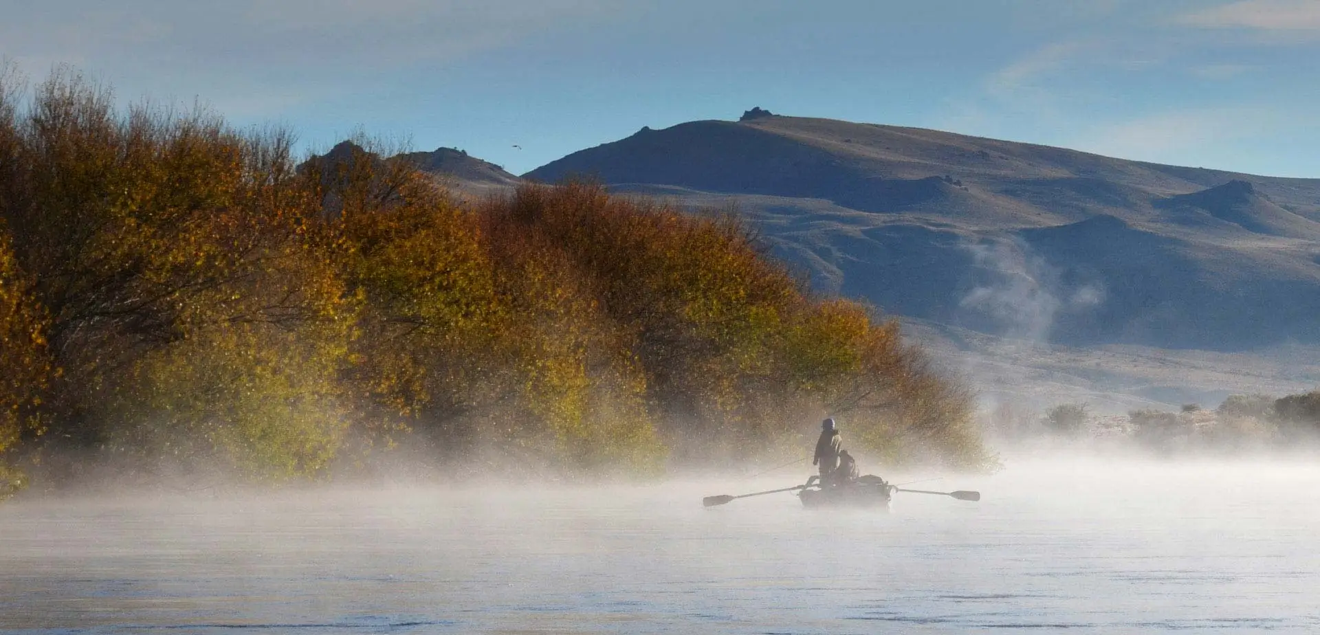 Trout fishing from a drift boat on the Limay River, Bariloche Patagonia, at sunrise.