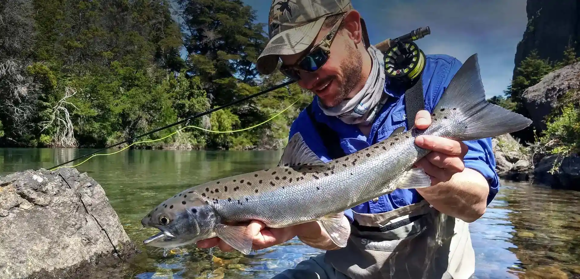 Fly fishing guide holding a land-locked salmon on Traful River near Bariloche, Patagonia Argentina