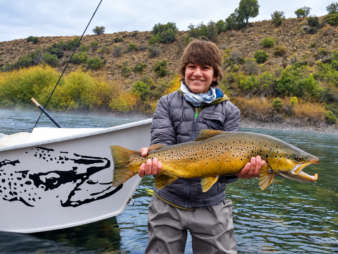 Pescador con una gran trucha marrón en el río Limay durante una salida de pesca con mosca en Patagonia