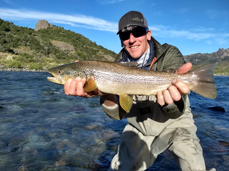 Pescador con una trucha marrón durante un viaje de pesca con mosca en el río Traful, cerca de Bariloche, Patagonia.