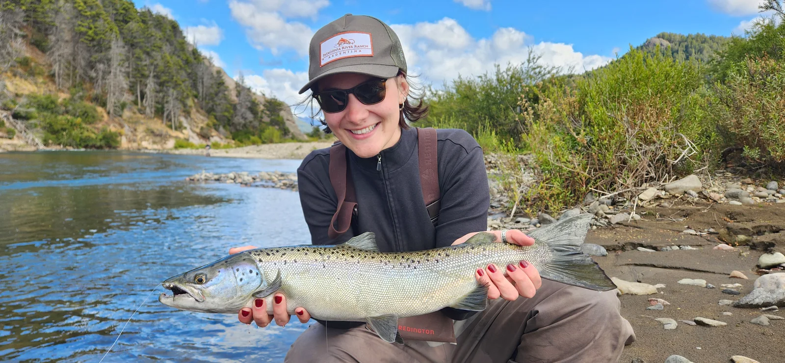 Pescadora con un salmón encerrado durante una salida guiada de pesca con mosca en el río Traful, Patagonia.
